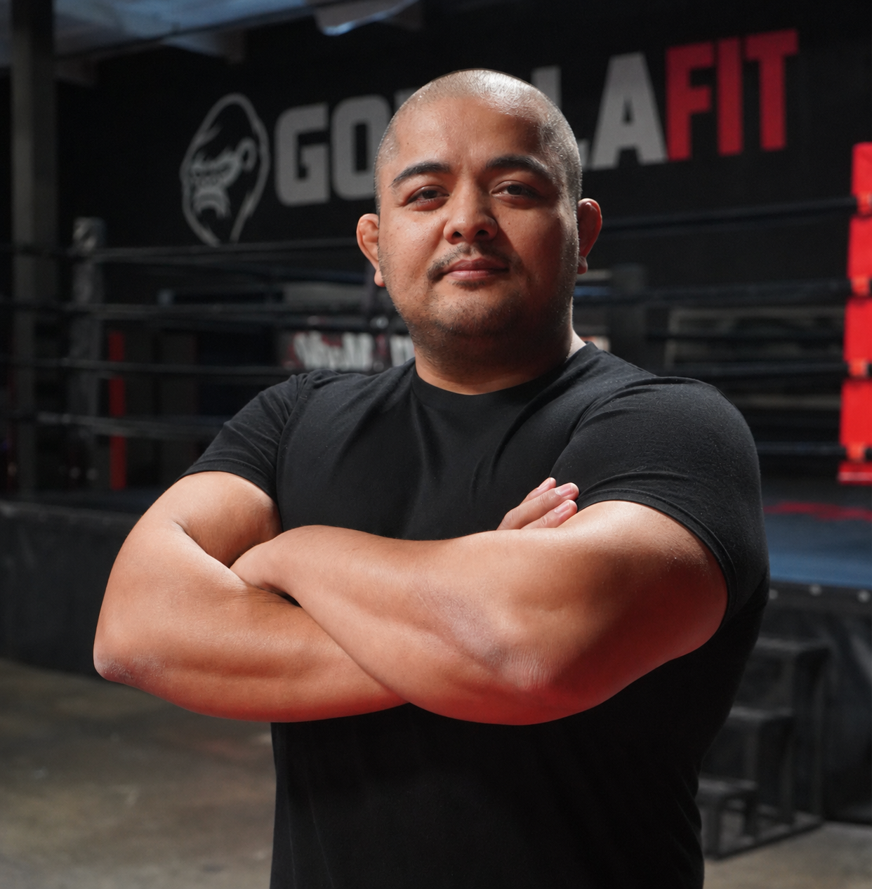 Joe T. standing with arms crossed beside the ring at his MMA gym